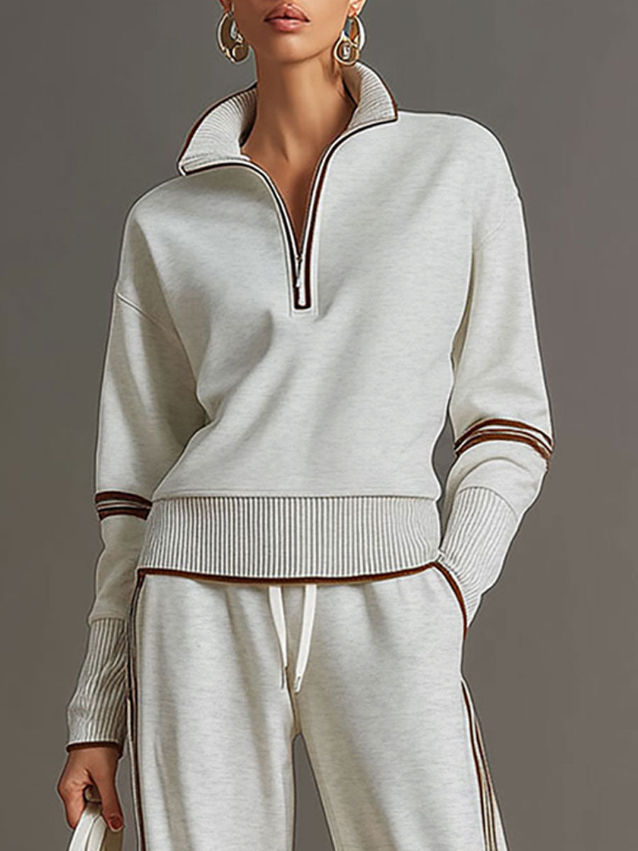 Sudadera gris y blanca de media cremallera con estilo vintage, acompañada de pantalones amplios